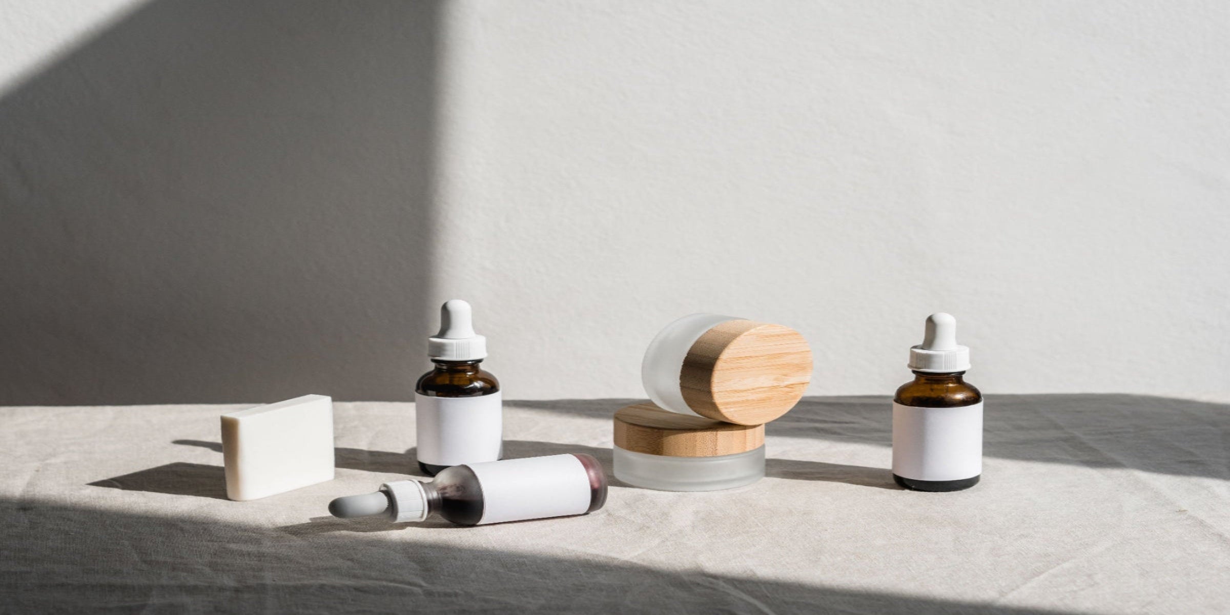 Skincare products including bottles and a wooden disc on a neutral background