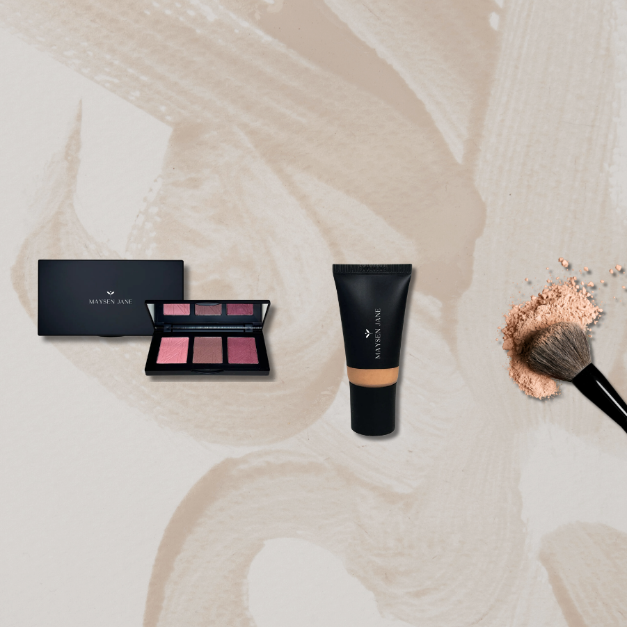 A flat-lay cosmetic set featuring a black Morphe Cosmetics palette, a black squeeze tube of foundation, and a makeup brush with pressed powder, arranged on a beige background with abstract paint strokes.